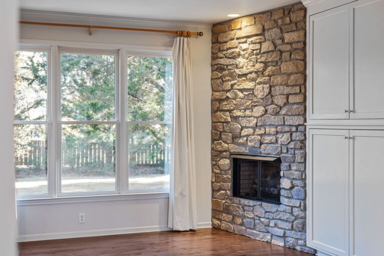 Natural stone fireplace built into a bright living room wall
